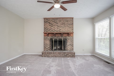 A room with a brick fireplace and a ceiling fan.