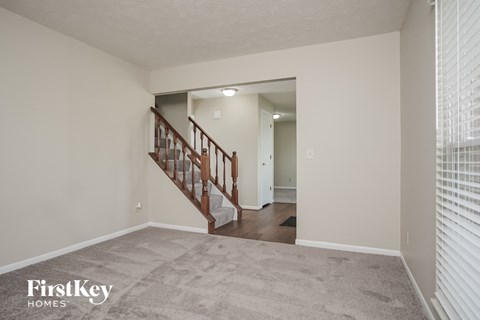 A spacious room with a staircase leading to the second floor.