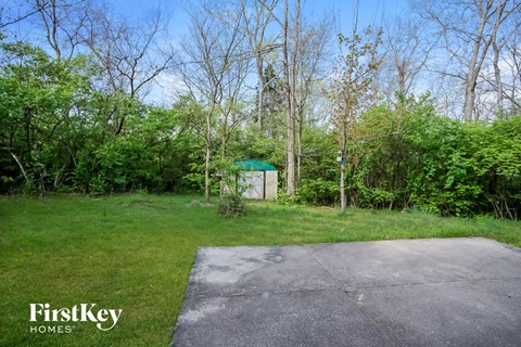A FirstKey Homes sign is on a grassy area with a concrete slab and trees in the background.