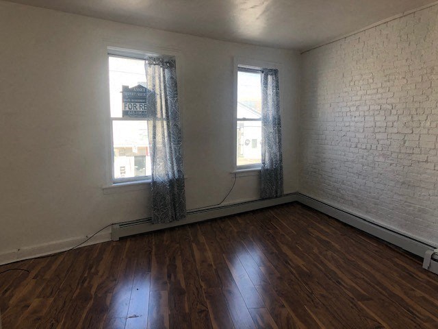 an empty room with a wood floor and two windows