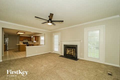A spacious living room with a fireplace and a ceiling fan.