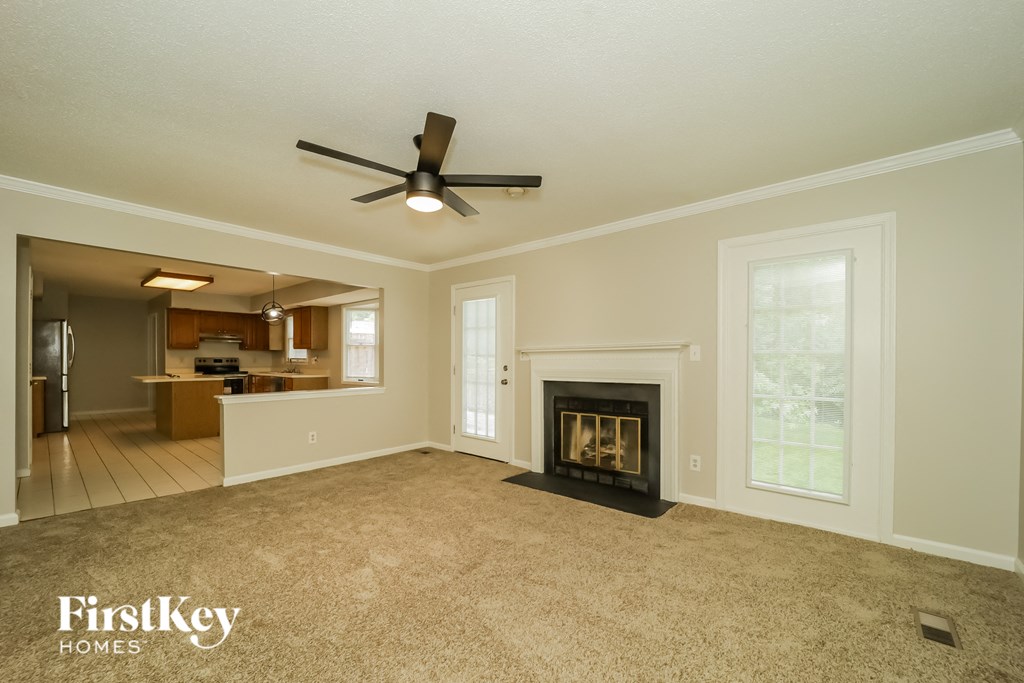 A spacious living room with a fireplace and a ceiling fan.