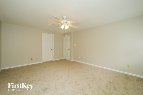 A spacious room with a ceiling fan and two doors.