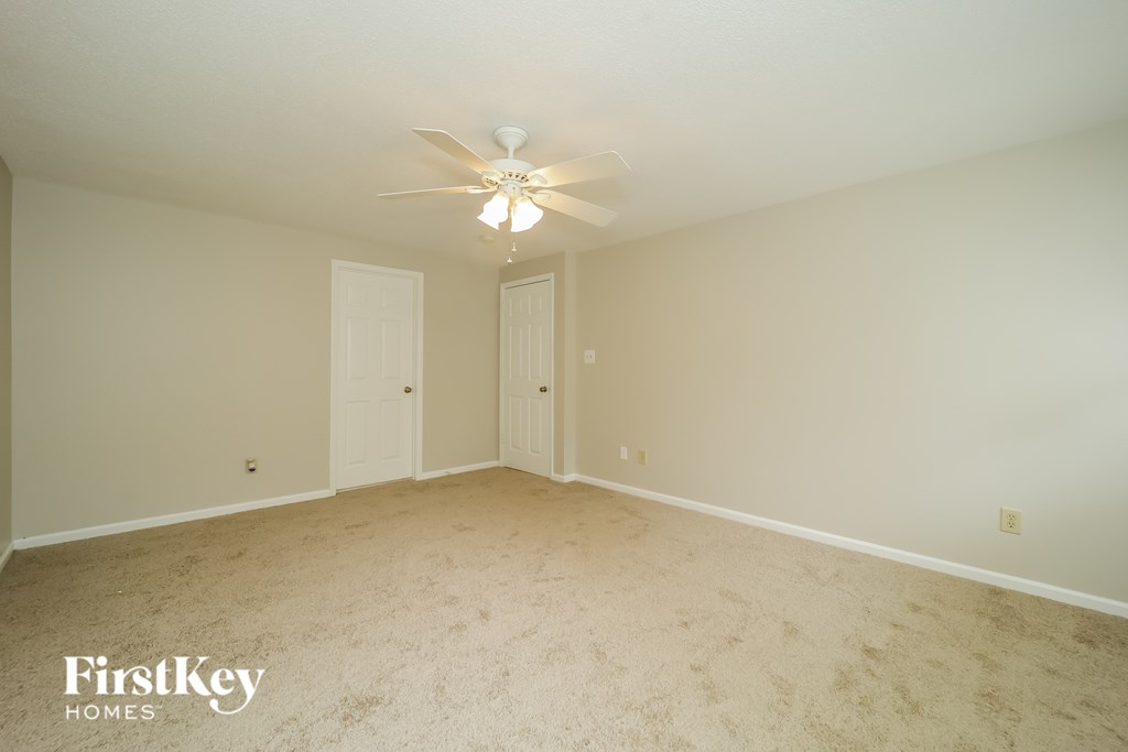 A spacious room with a ceiling fan and two doors.