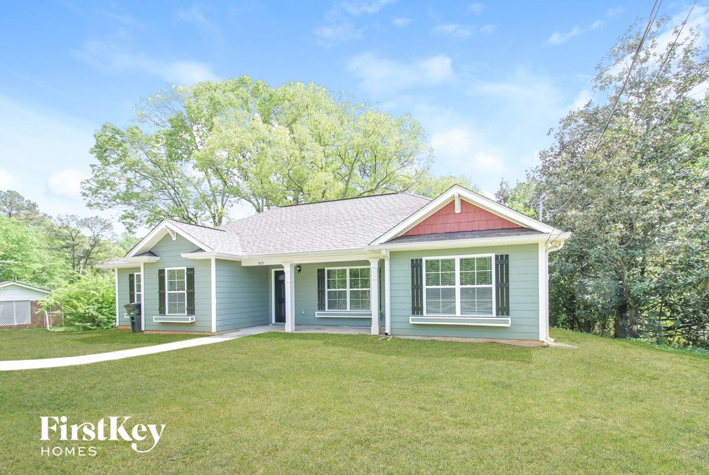 a blue house with a yard and a red roof