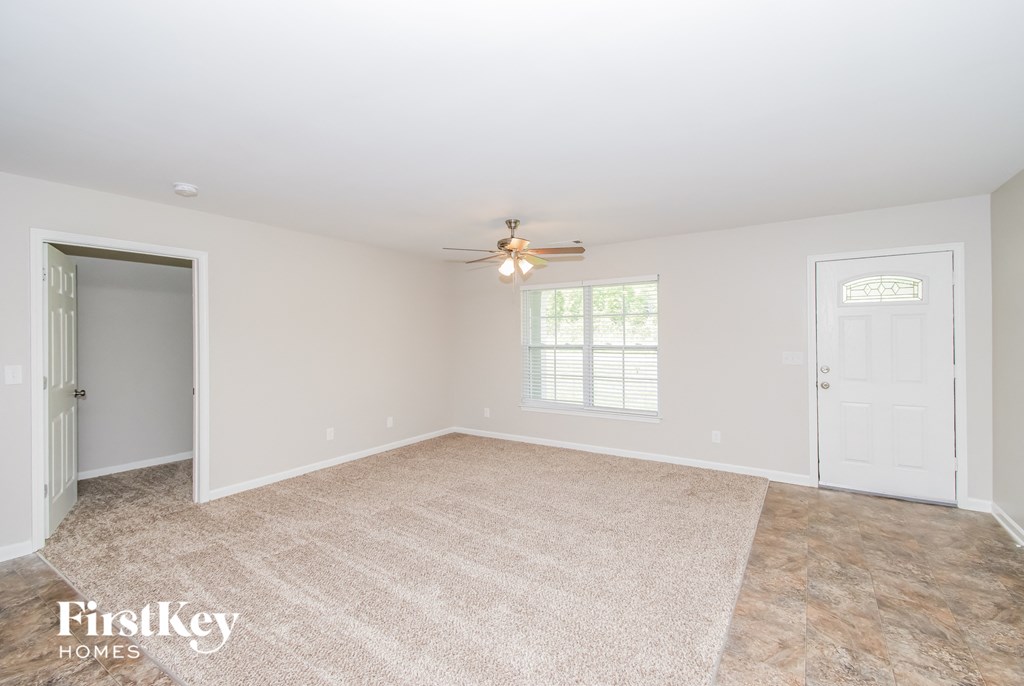 a empty living room with a ceiling fan and a door to a closet