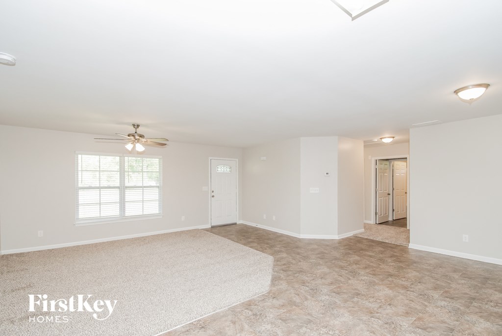 a empty living room with a ceiling fan and a rug
