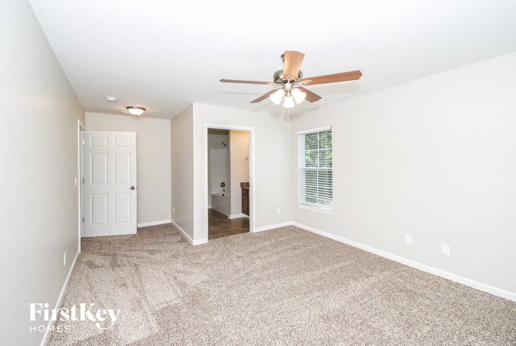 a spacious living room with carpet and a ceiling fan