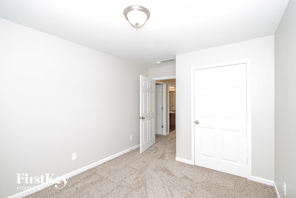 a clean and empty room with a white door and carpeted floor