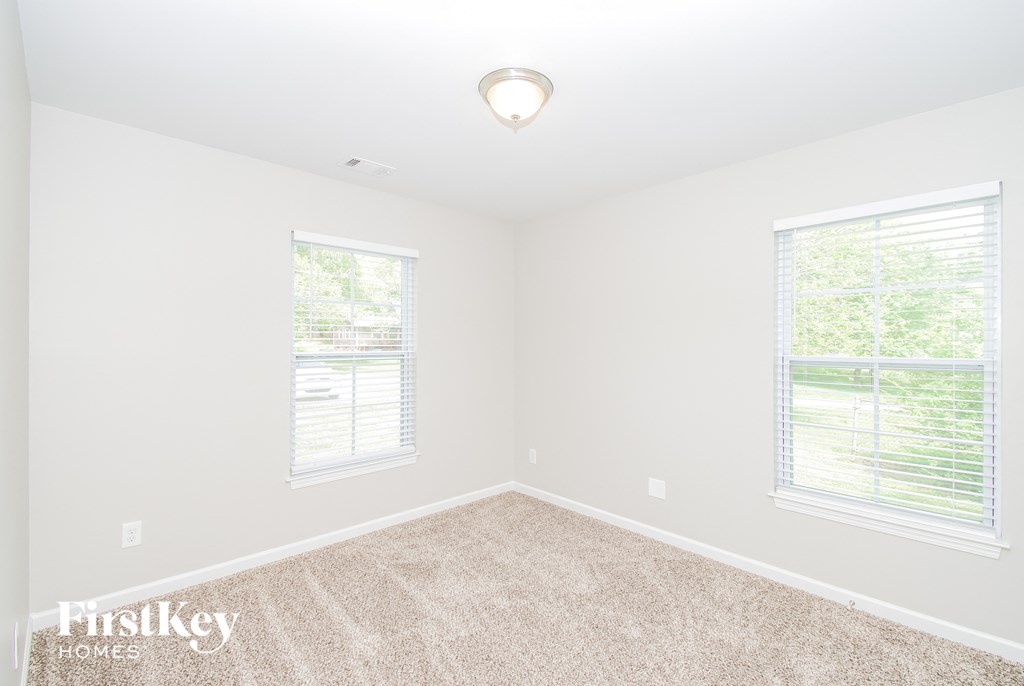 a bedroom with two windows and a carpeted floor