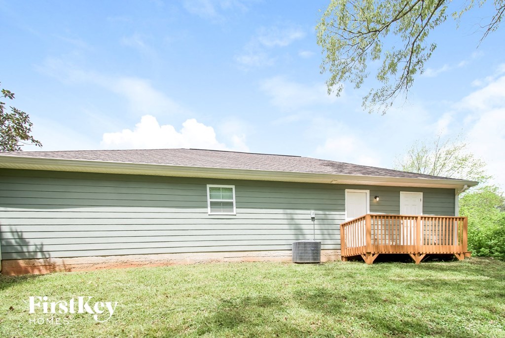 the front of a green house with a porch and a deck