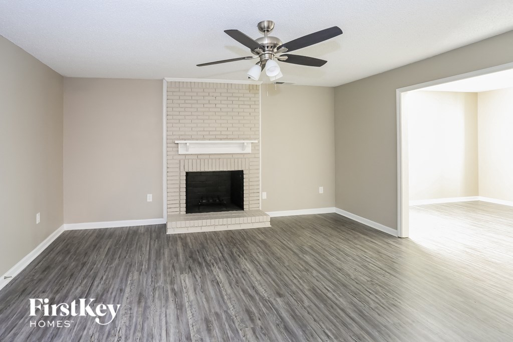 A spacious room with a fireplace and a ceiling fan.