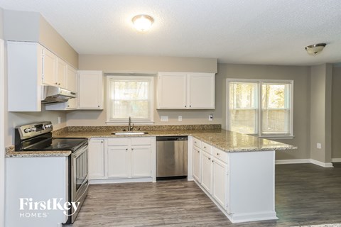 A kitchen with white cabinets and a granite countertop.