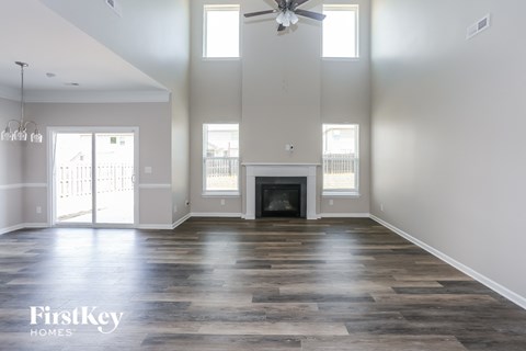an empty living room with a fireplace and a ceiling fan