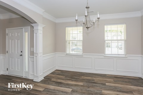 a dining room with white wainscoting and a chandelier