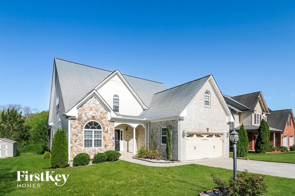 a white brick house with a gray roof and a white garage