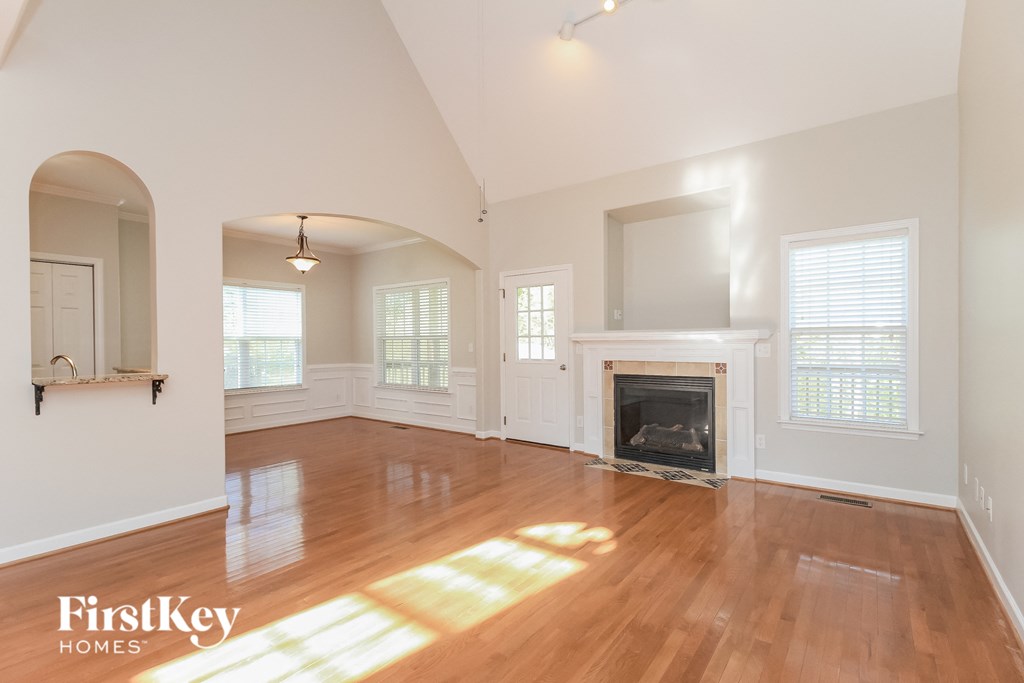 an empty living room with a fireplace and wooden floors