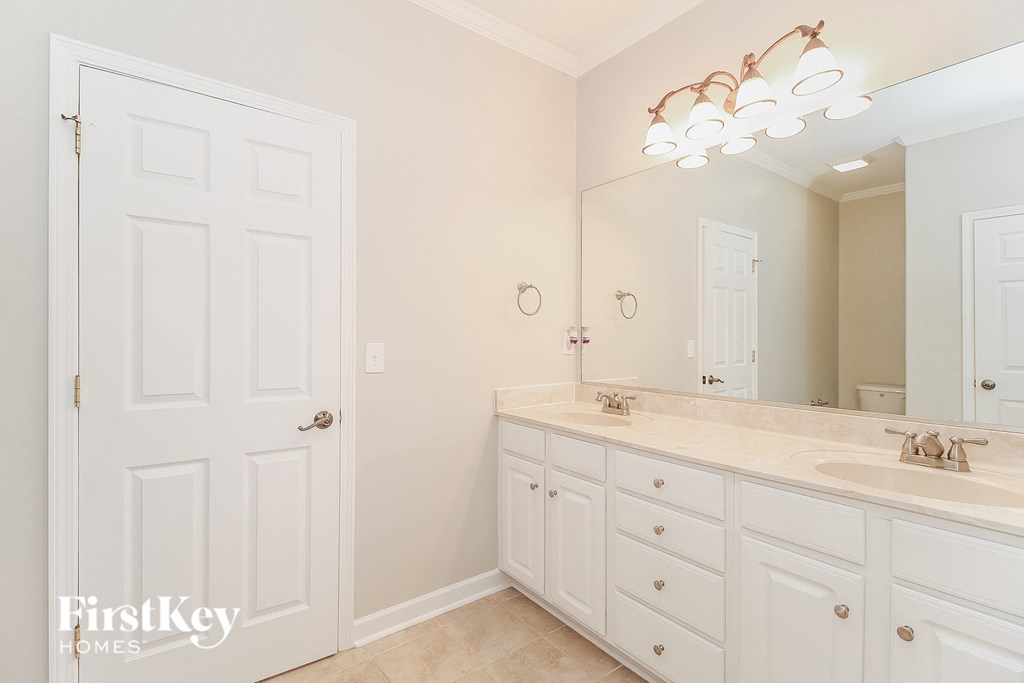 a bathroom with white cabinets and a sink and a mirror