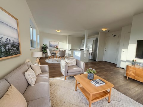 A living room with a grey couch, a wooden coffee table, and a painting on the wall.