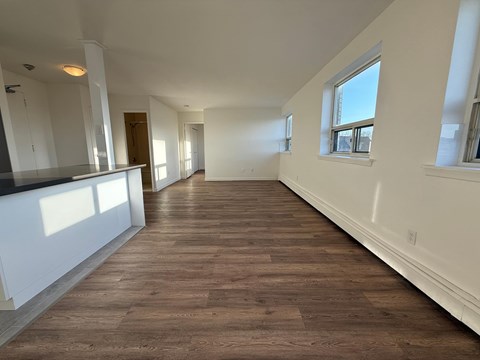 A long, empty room with wooden floors and white walls.