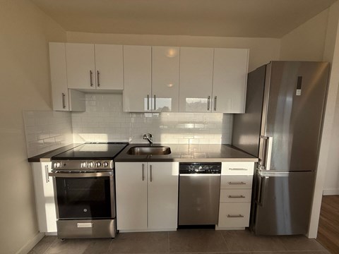 A kitchen with a stainless steel refrigerator, oven, and sink.
