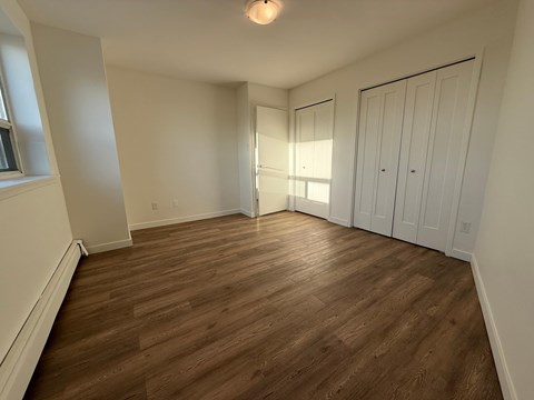 A room with wooden flooring and white walls.