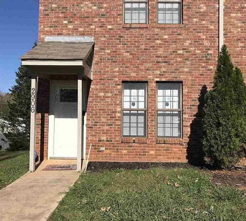 A red brick house with a white door and windows.