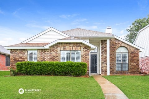 a brick house with a green lawn and grass