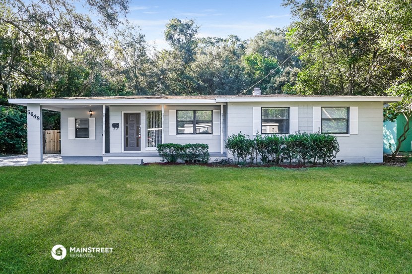 a small white house with a lawn and trees