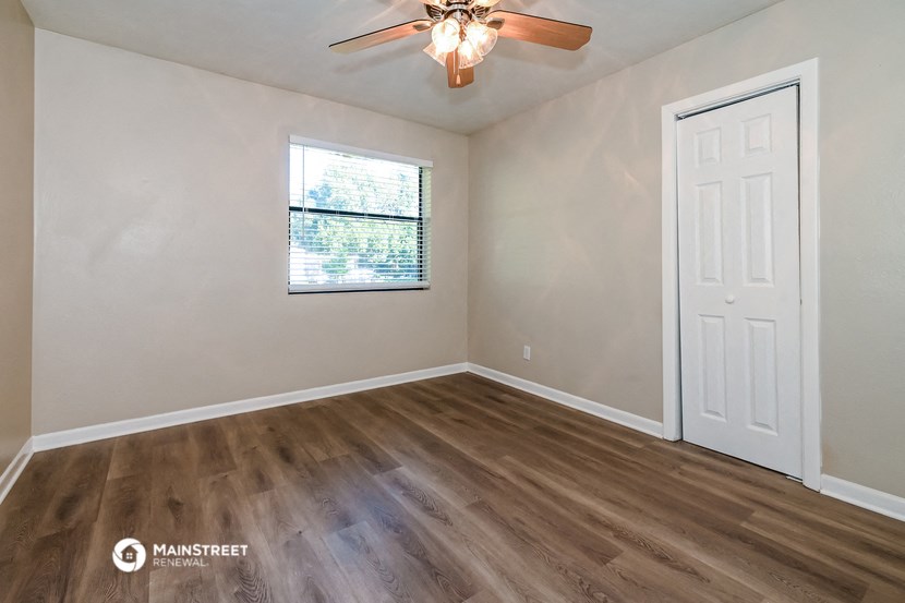 the living room of an empty home with a window and a ceiling fan