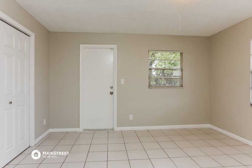 an empty living room with a white tile floor and a white door