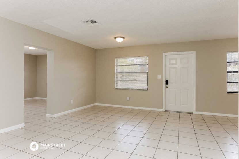 an empty living room with a white tile floor and a white door