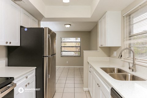 a kitchen with white cabinets and a sink and a refrigerator