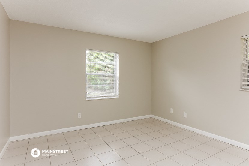 an empty living room with a tiled floor and a window