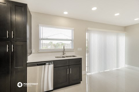 a kitchen with black cabinets and a sink and a window