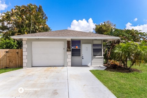 a bungalow with a driveway and a palm tree