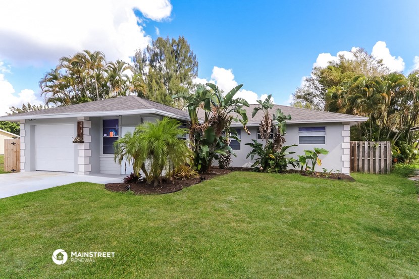 a white house with a lawn and palm trees