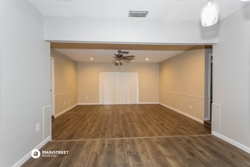 the spacious living room with a ceiling fan and wood flooring