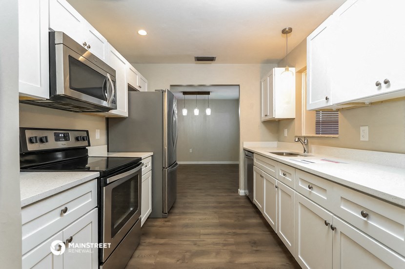 an empty kitchen with white cabinets and stainless steel appliances