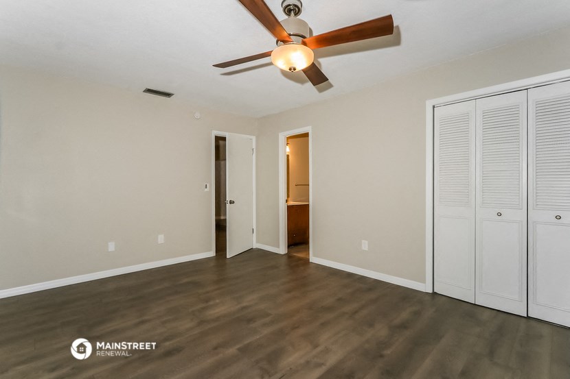 the spacious living room with ceiling fan and closet