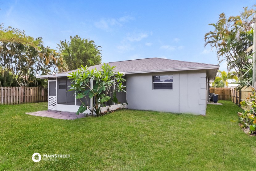 a small white house with a yard and a palm tree