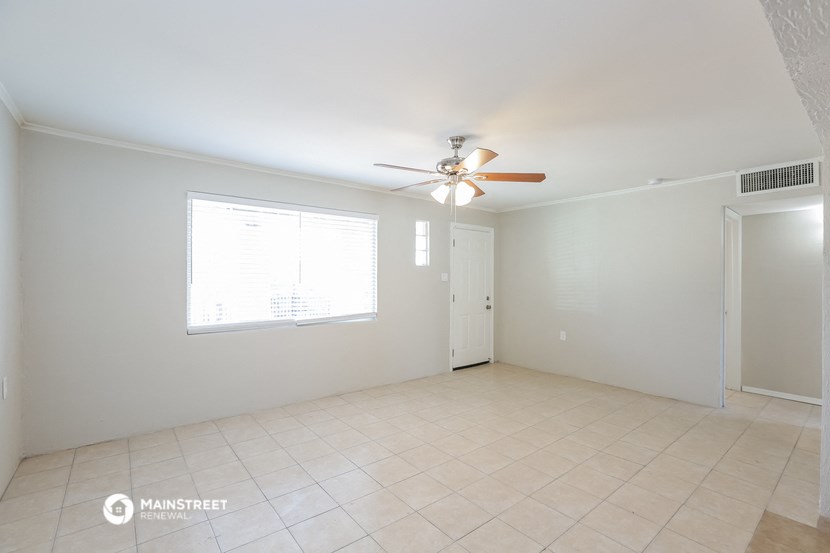 an empty living room with a ceiling fan and a window