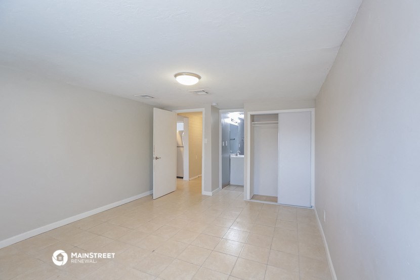 a renovated living room and hallway with white walls and a tiled floor