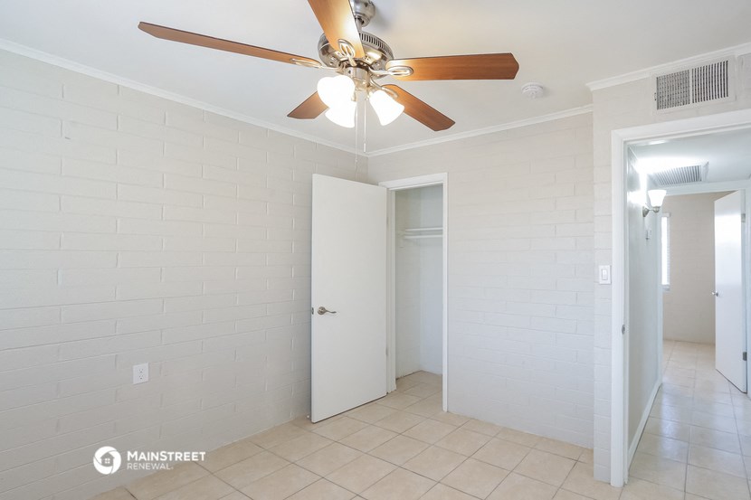 a living room with a ceiling fan and a door to a bathroom