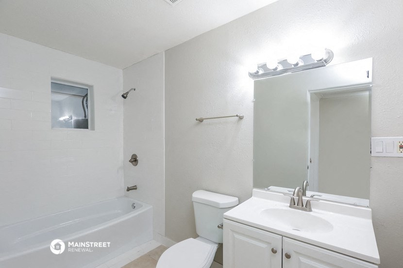 a white bathroom with a white sink and toilet and a bath tub