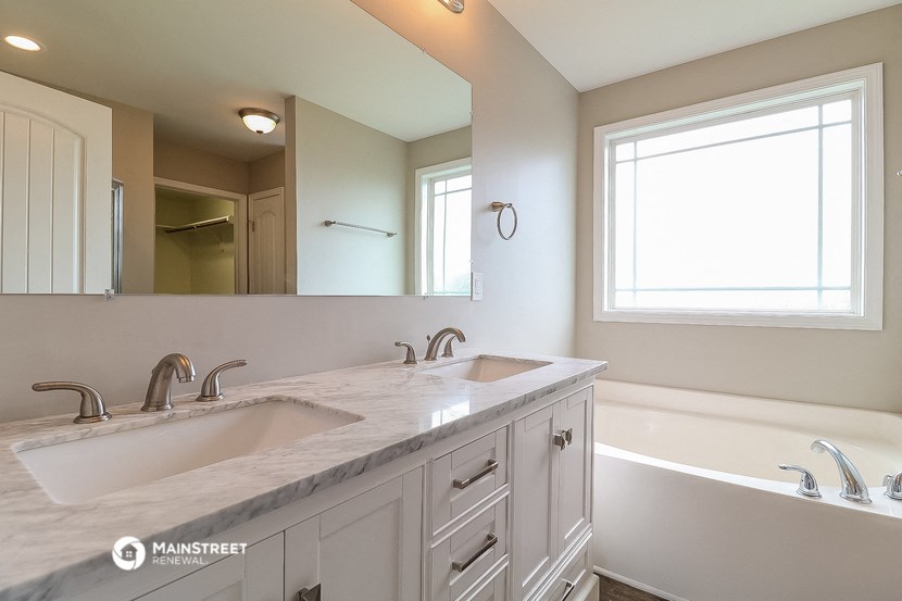 a bathroom with two sinks and a tub and a large mirror