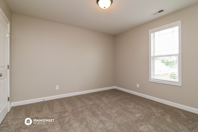 the spacious living room with carpeting and a window