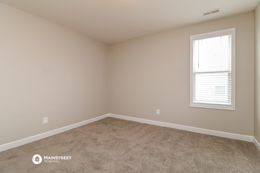an empty room with a window and carpet