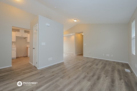 the living room and kitchen of an apartment with wood flooring