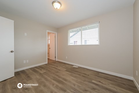 the living room of an apartment with wood flooring and a window